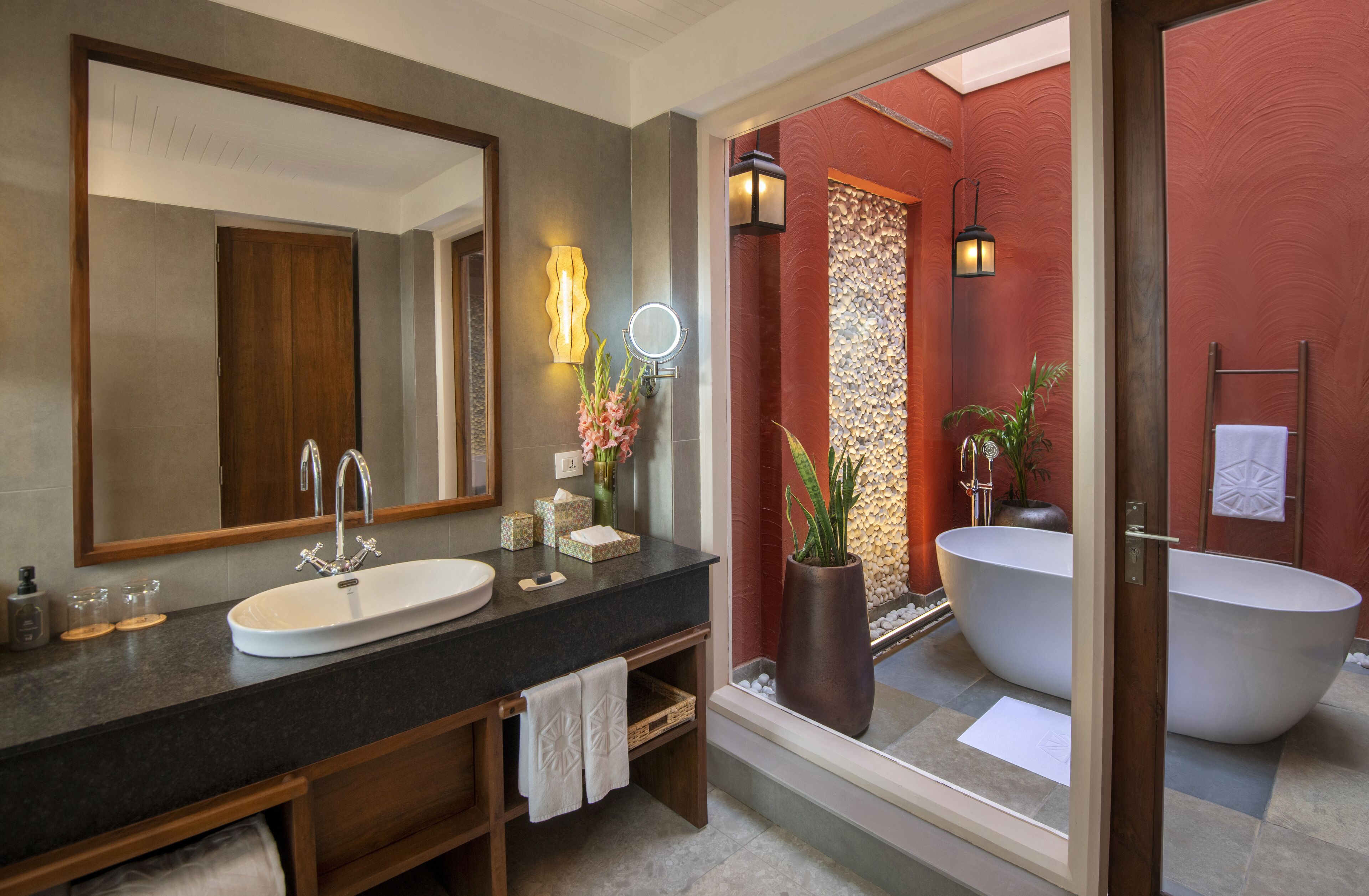A modern bathroom with a large mirror, a sink, a bathtub, and a vanity with a towel rack.