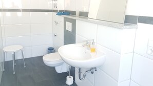 Ein modernes Badezimmer mit einem weißen Waschbecken, einem Spiegel und einer Toilette.