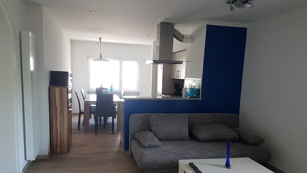 Ein Wohnzimmer mit einer Couch, einem Couchtisch und einem Fernseher auf einem Standfuß.