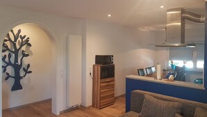 Ein modernes Wohnzimmer mit einem Holzkabinett, einer Couch und einer Wanddekoration mit Baumdesign.