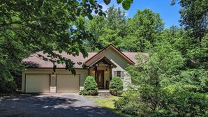 A single-story house with a garage, surrounded by dense greenery. - 'Brookmont Lodge' Right Off Sugar Golf Course! (Sugar Mountain)