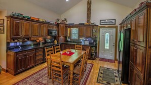 A spacious kitchen with wooden cabinets, a dining table, and a large window. - 'Brookmont Lodge' Right Off Sugar Golf Course! (Sugar Mountain)