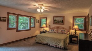 A bedroom with a bed, two bedside tables, a ceiling fan, and large windows with blinds. - 'Brookmont Lodge' Right Off Sugar Golf Course! (Sugar Mountain)