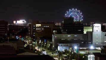 A nighttime cityscape with illuminated buildings and a prominent Ferris wheel.