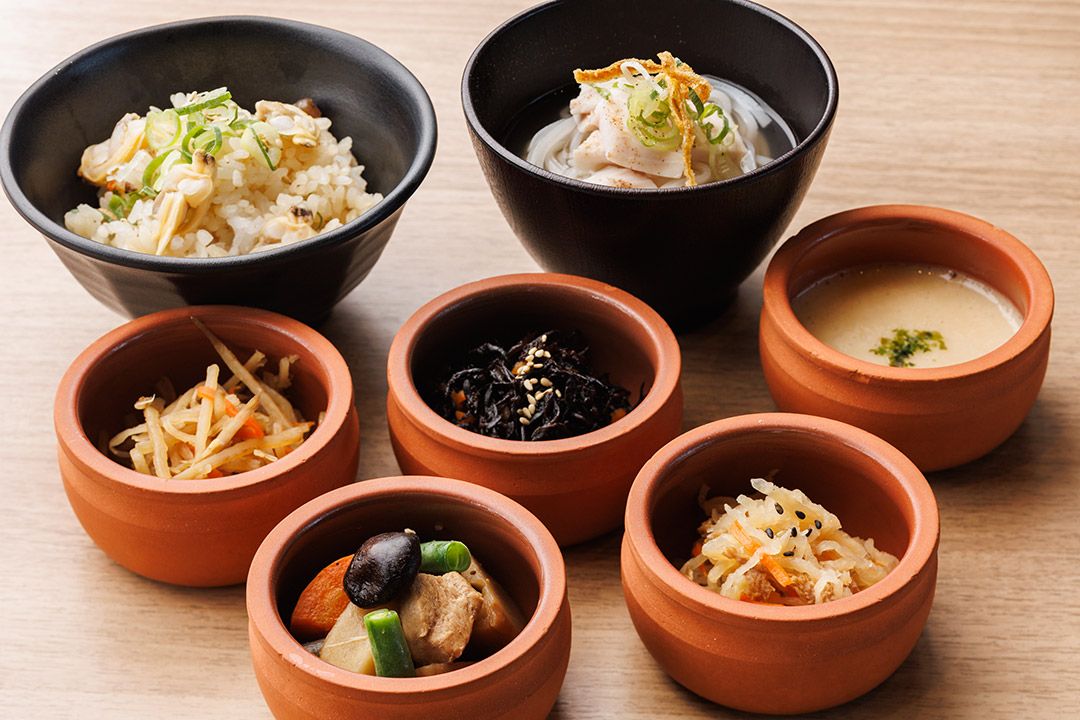 A variety of dishes in different bowls, including rice, soup, and vegetables.