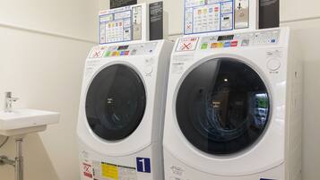 Two front-loading washing machines with control panels, a sink, and a wall-mounted sign.