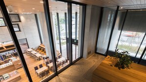 A modern interior with glass walls, a seating area with tables and chairs, and a wooden bench. - JR East Hotel Mets Premier Tokyo Bay Shinkiba (Tokyo)