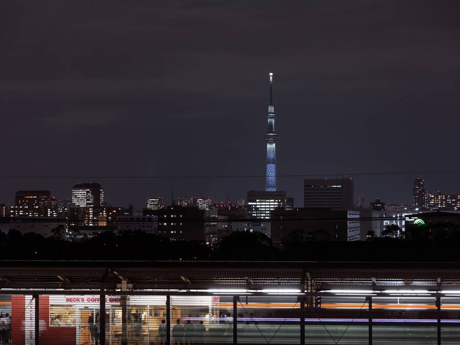 A nighttime cityscape with a prominent tower lit up against the sky.