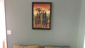 Una habitación con sofá cama, dos almohadones estampados y un cuadro en la pared.