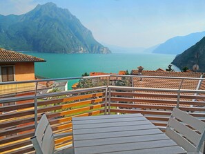 A balcony with a table and chairs overlooking a lake and mountains. - Luxurious Penthouse: Villa Letizia (Castro)