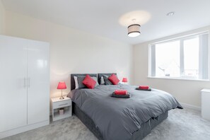 A bedroom with a bed, nightstands, a wardrobe, and a window.