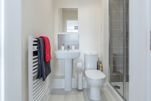 A modern bathroom with a white sink, toilet, and shower.