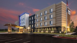 A multi-story hotel with a modern design, featuring a prominent entrance with a curved canopy and a stone pillar. - Fairfield Inn & Suites by Marriott Little Rock Airport (Little Rock)