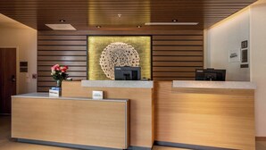 A reception desk with a modern design, featuring a wooden finish and a decorative wall piece above it. - Fairfield Inn & Suites by Marriott Little Rock Airport (Little Rock)