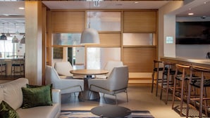 A modern hotel lobby with a seating area, a bar, and a television screen. - Fairfield Inn & Suites by Marriott Little Rock Airport (Little Rock)