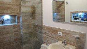 A bathroom with a glass shower enclosure, a sink, and a mirror. - Laureles Apartments! (Medellín)