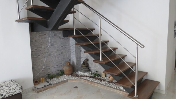 A modern staircase with a metal railing, wooden steps, and a stone wall. - Laureles Apartments! (Medellín)