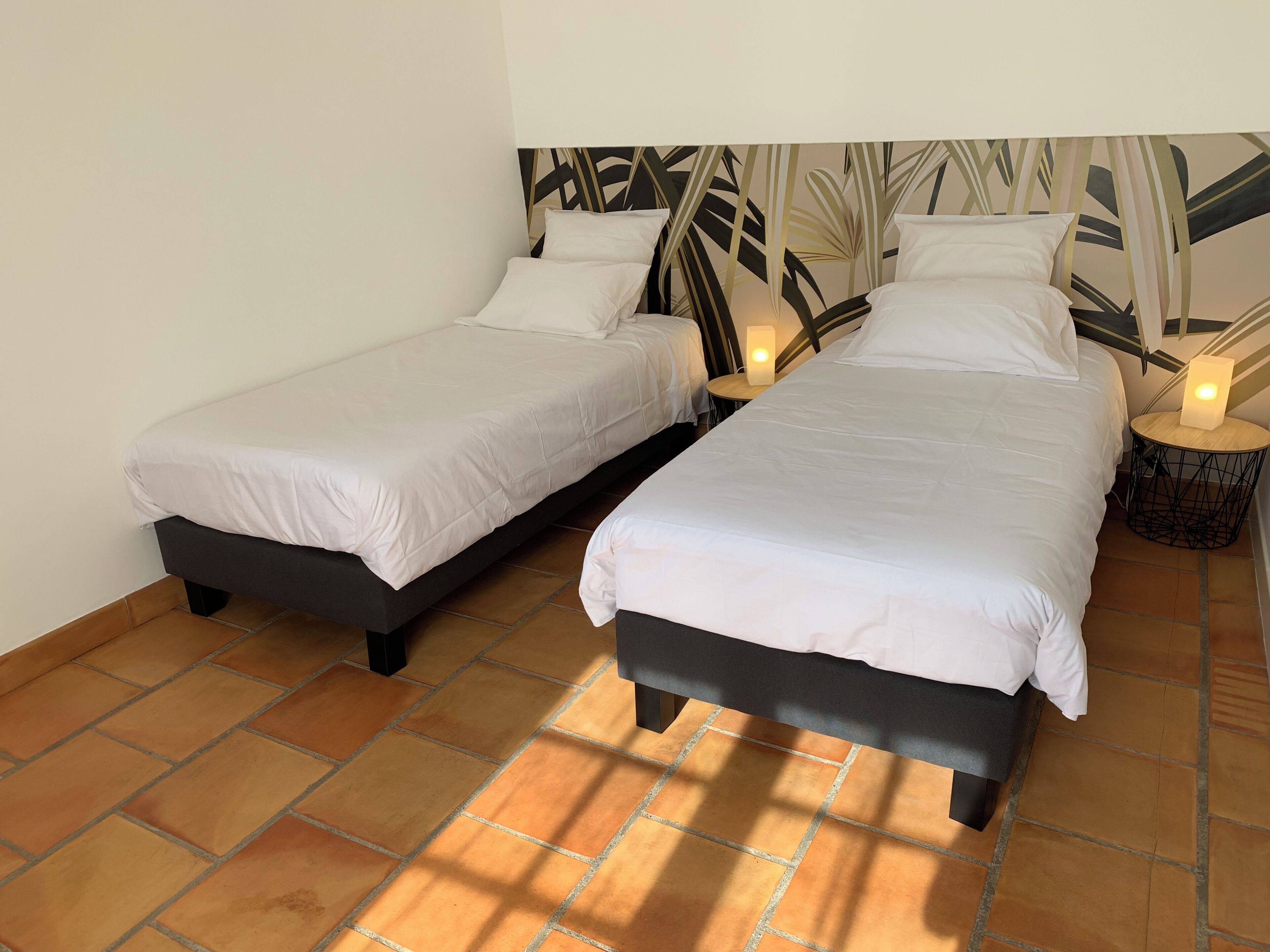 Ein Zimmer mit zwei Einzelbetten, einer Wand mit Muster und einem gefliesten Boden.