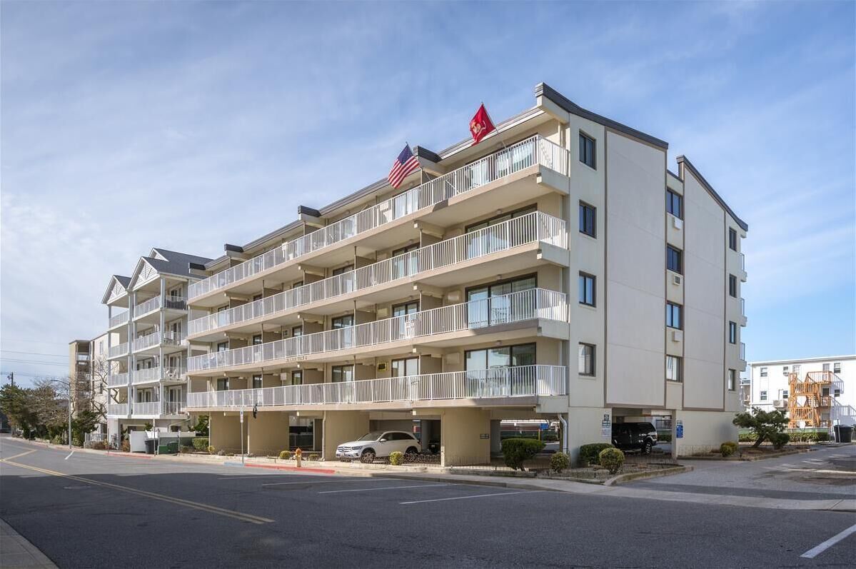 Een meerlaags hotel met balkons, een parkeergarage en vlaggen op het dak.