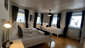 A bedroom with a bed, bedside table, lamp, and a small desk.