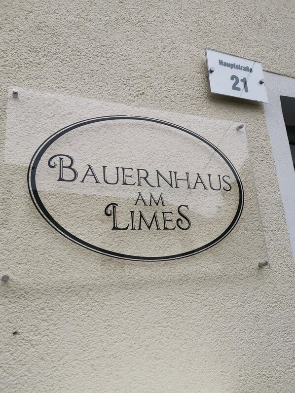 A building sign with "BAUERNHAUS AM LIMES" and a street sign indicating "Hauptstraße 21". - Romantic farmhouse on the Limes (Laimerstadt)
