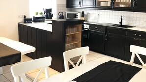 A compact kitchen with dark cabinets, a microwave, a coffee maker, and a dining area with a table and chairs.