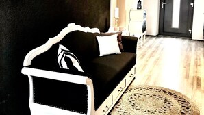 A modern living room with a black and white sofa, a woven rug, and a wall decorated with animal skulls.