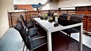 An outdoor patio with a table and chairs, a decorative vase, and a solar panel on a building in the background.
