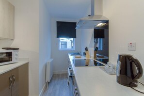 Apartamento família, várias camas, vista para a baía, no piso térreo | Cozinha privada | Geladeira, micro-ondas, fogão, cooktop