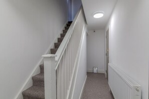 A staircase with white railings and carpeted steps leading to a landing.
