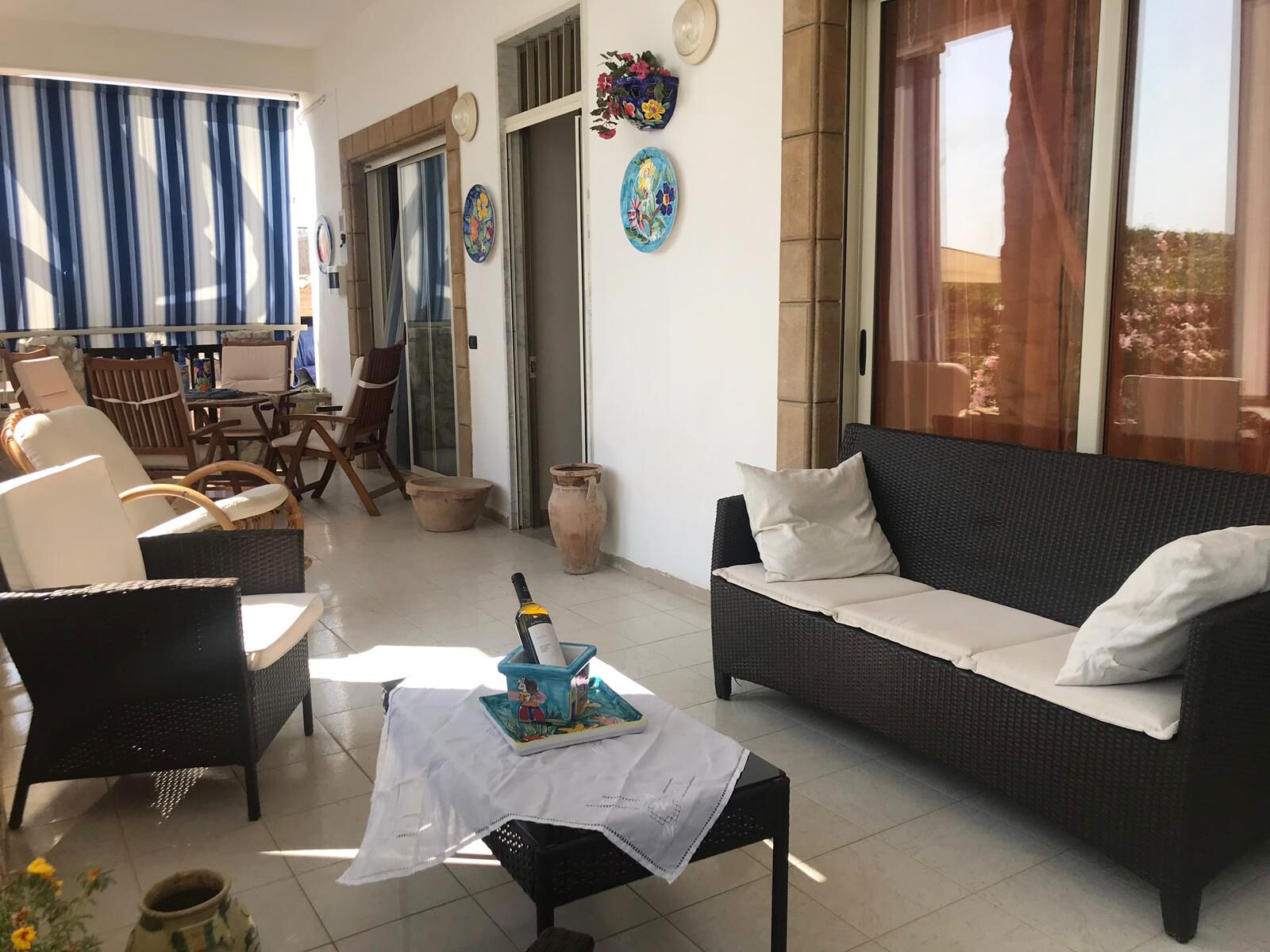 Un salón soleado con sofá, sillas, una mesa y vistas a través de un ventanal.