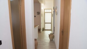 A hallway with wooden doors, a light-colored floor, and two large clay pots. - Villa Eden Luxore (SCIACCA)