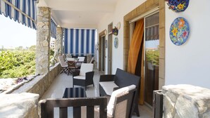 A balcony with wicker furniture, stone walls, and a view of greenery. - Villa Eden Luxore (SCIACCA)