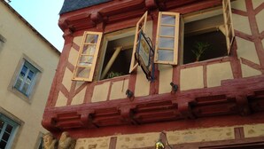 Ein traditionelles Fachwerkhäuschen mit mehreren Fenstern, von denen einige mit Fensterläden versehen sind, und einem sichtbaren Schild, das auf ein Geschäft hinweist.