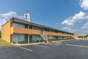 A motel with a parking lot, a staircase leading to the entrance, and a clear sky. - Rodeway Inn Kingston Springs (Kingston Springs)