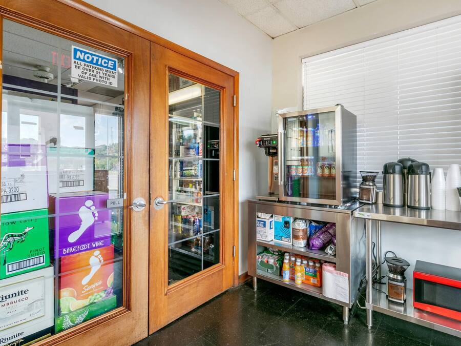 A room with a wooden door, a vending machine, a refrigerator stocked with beverages, and a coffee machine.