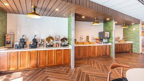 Une cuisine moderne avec des meubles en bois, un parquet disposé en motif à chevrons et un îlot central doté d’appareils électroménagers.