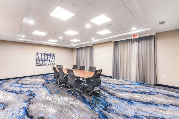 A conference room with a large table, chairs, and a ceiling with recessed lighting.