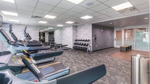 Une salle de sport équipée de tapis de course, d’haltères et d’autres appareils d’exercice.