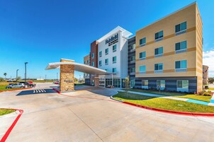 A Fairfield Inn & Suites hotel with a modern design, featuring a covered entrance and a parking lot.
