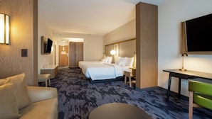A hotel room with a bed, a desk, a chair, a sofa, and a TV. - Fairfield Inn & Suites by Marriott Greenville Spartanburg/Duncan (Duncan)