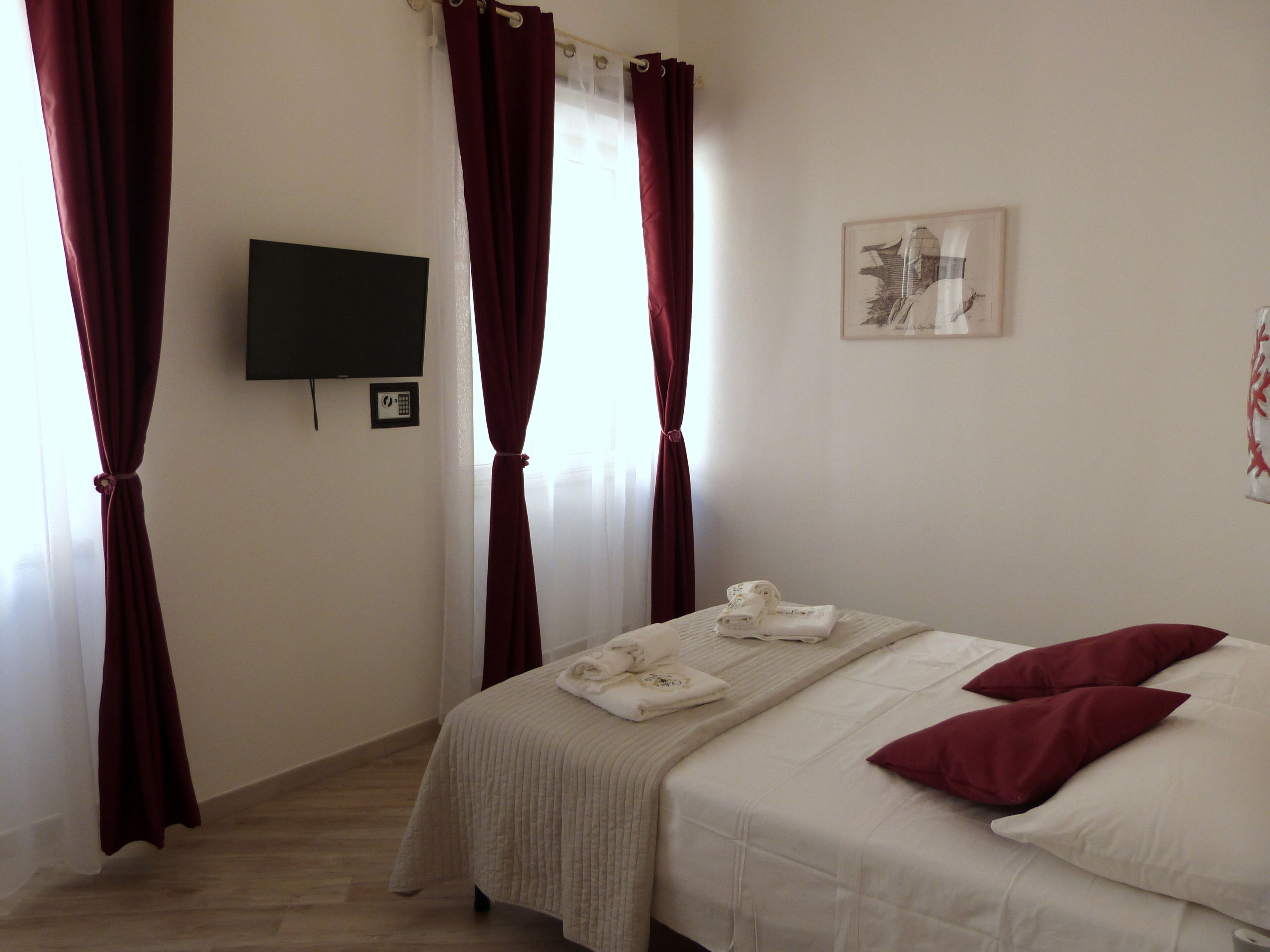 A hotel room with a bed, a TV, and a painting on the wall.