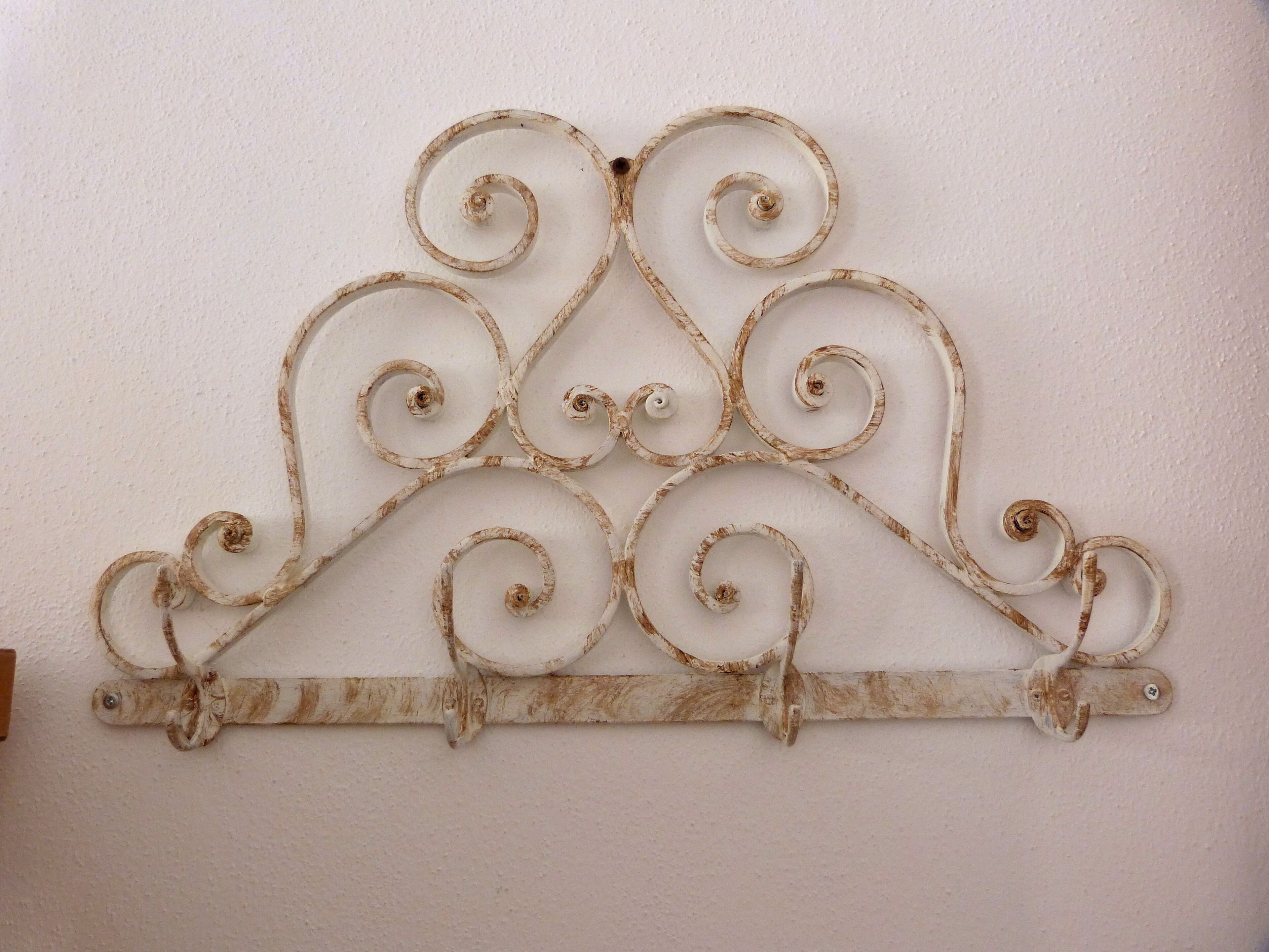 A decorative metal wall piece with a central arch and symmetrical swirls.