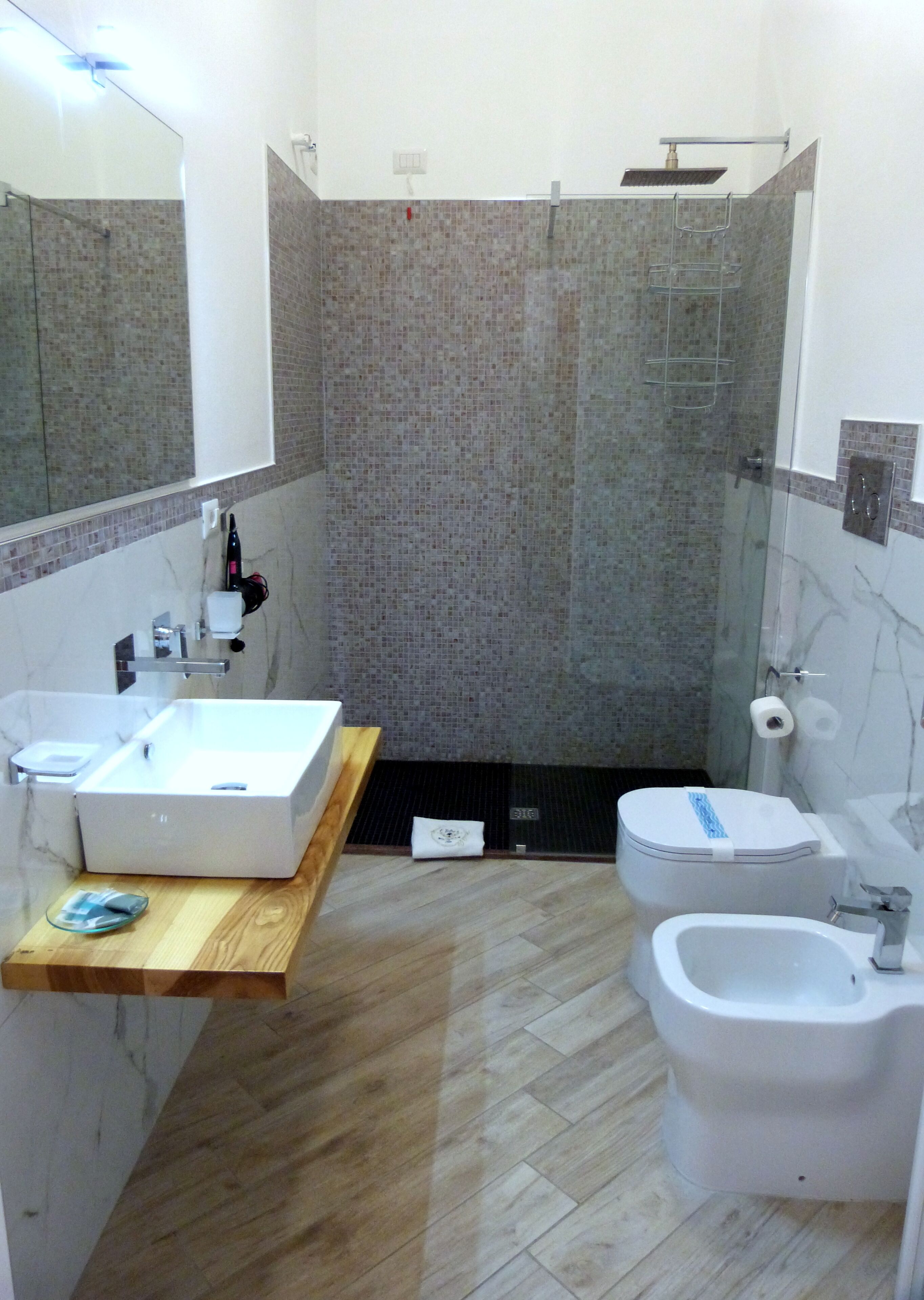 Un bagno moderno con una doccia spaziosa, un lavandino bianco, un bidet e un water.