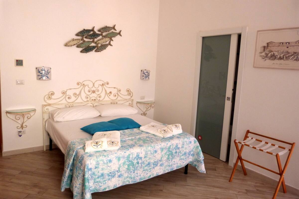 A bedroom with a bed, a bedside table, a wall decoration, and a door.
