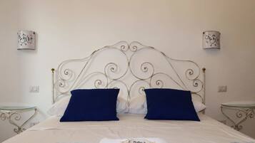 Una cama bien hecha con un tablero de cabecera decorativo, dos mesitas de noche y apliques de pared.