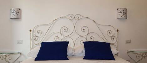 A neatly made bed with a decorative headboard, two bedside tables, and wall sconces.