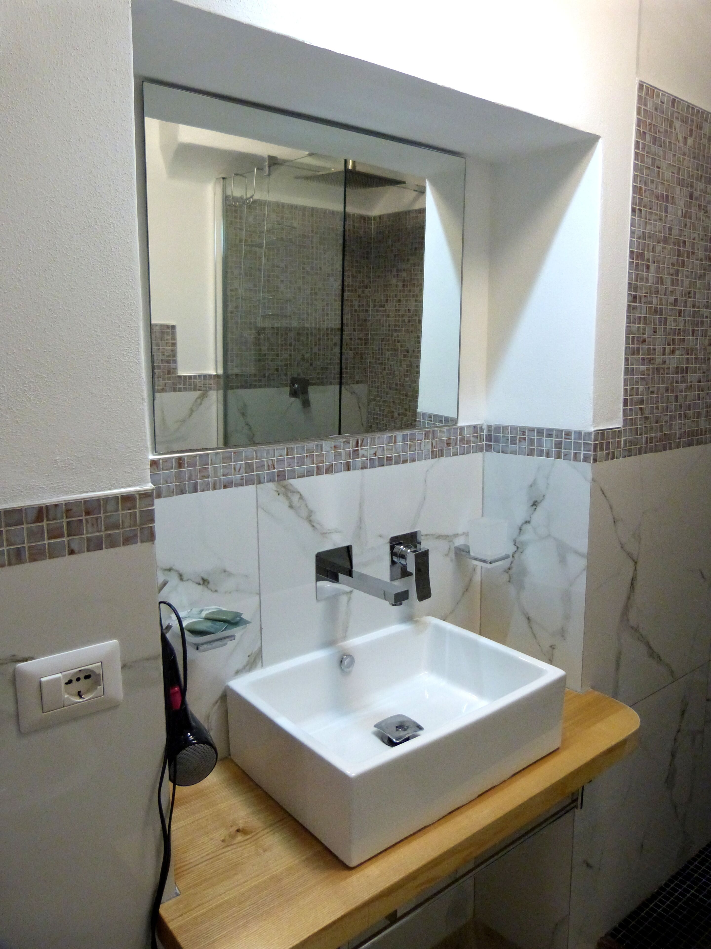 Baño con lavamanos blanco, espejo y ducha.