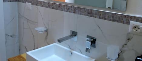 Un baño con un lavabo blanco, encimera de madera y un espejo encima.