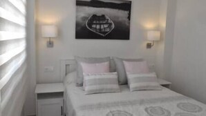 Ein Schlafzimmer mit einem Bett, zwei Nachttischlampen, einem Nachttisch und einem Wandbild.
